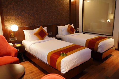 a hotel room with two beds and a chair at Saugandhika West Gate in Wayanad