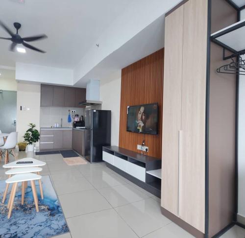 a living room with a kitchen with a tv on a wall at Alinea Suites Shah Alam Seksyen 14 in Shah Alam