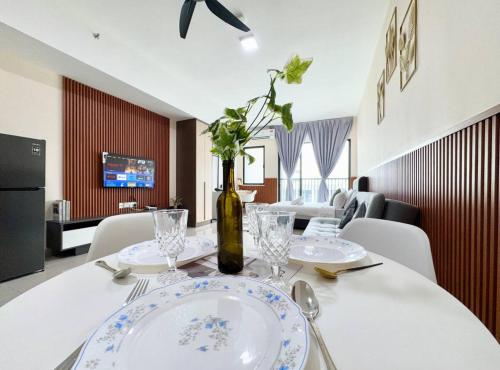 a table with plates and a bottle of wine on it at Alinea Suites Shah Alam Seksyen 14 in Shah Alam