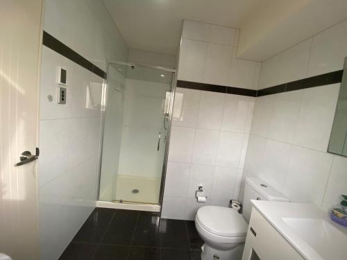 a white bathroom with a shower and a toilet at Self Contained Room in Hillsborough in Auckland