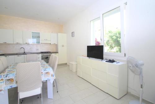 a white kitchen with a table and a window at Palau Fonte Vecchia Apartment in Palau