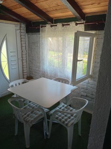 a white table and chairs in a room with windows at Apartmani Primus in Bosanska Gradiška