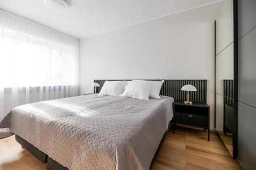 Un dormitorio blanco con una cama grande y una ventana. en Centrum Apartment Nikolai, en Pärnu