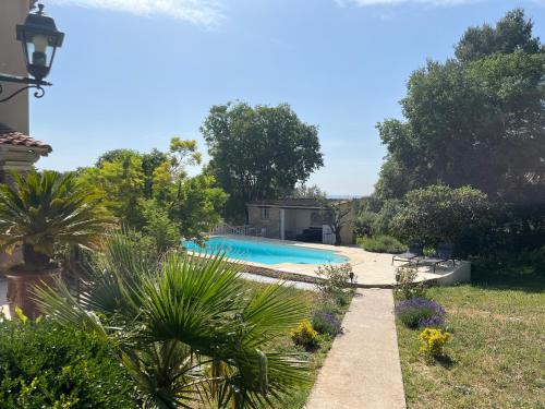 une piscine dans un jardin planté de plantes et d'arbres dans l'établissement Le mazet en été en garrigue nimoise et parking, à Nîmes