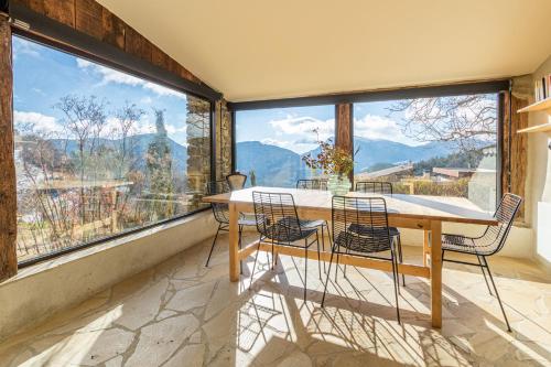 - une table et des chaises dans une pièce dotée de grandes fenêtres dans l'établissement Jolie maison en plein coeur des bois et lavande pour 5 personnes, à Teyssières