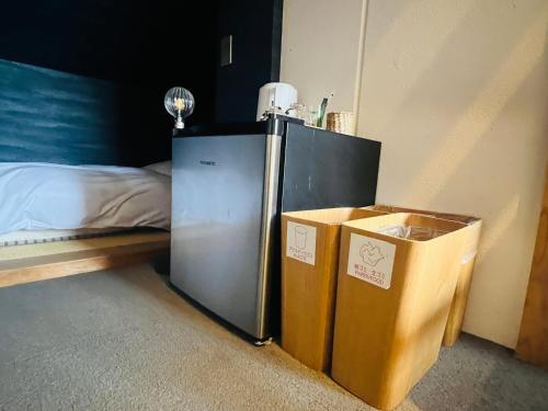 a room with a refrigerator and two boxes next to a bed at SIMA inn in Onomichi