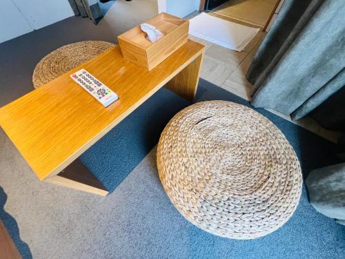 a wooden table with a rattan stool and a hat at SIMA inn in Onomichi