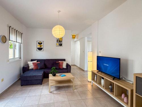 a living room with a blue couch and a tv at Sunny Villa with Hot Tub, Garden and 2 Bedrooms, 5 Minutes to the Beach in Pyla