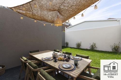 a wooden table and chairs in a backyard with an umbrella at 14th Street Villa - Espinho in Espinho