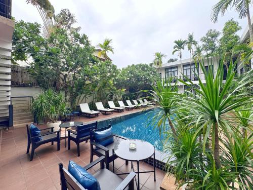 a hotel patio with tables and chairs and a pool at The Bliss Angkor in Siem Reap