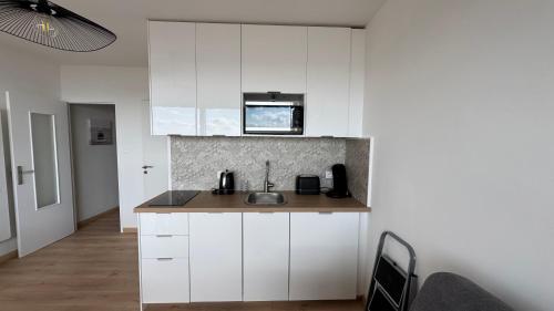 une cuisine avec des armoires blanches et un évier dans l'établissement Appartement Marina FACE MER, à Saint-Jean-de-Monts