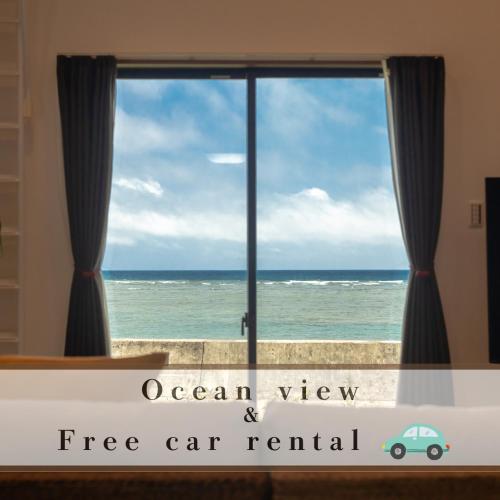 a window with a view of the ocean and a car rental sign at 石垣島一棟貸し 汐 in Ishigaki Island
