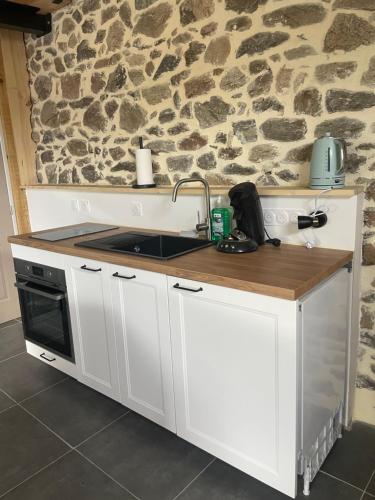 une cuisine blanche avec un évier et une cuisinière dans l'établissement Unik à Ruynes, à Ruynes-en-Margeride