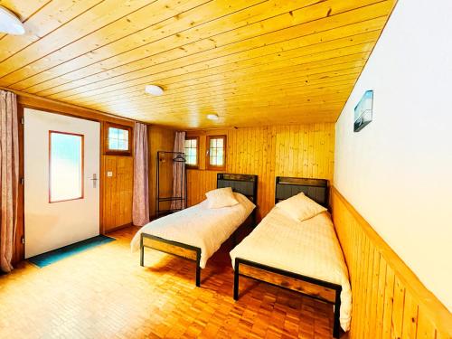 two beds in a room with a wooden ceiling at Gästehaus Milital in Innertkirchen