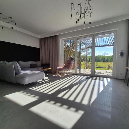 a living room with a couch and a large window at Strefa Natur dom z jacuzzi na wyłączność in Matyty