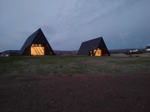 two black buildings sitting on top of a green field at Wild Atlantic Pods in Portmagee