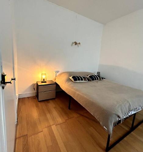 une chambre avec un lit et une table de chevet avec une lampe dans l'établissement Le Bara - Appartement proche des Grands Buffets et des Halles, à Narbonne