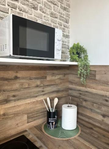 une cuisine équipée d'un four micro-ondes et d'un comptoir avec des ustensiles. dans l'établissement Le Bara - Appartement proche des Grands Buffets et des Halles, à Narbonne