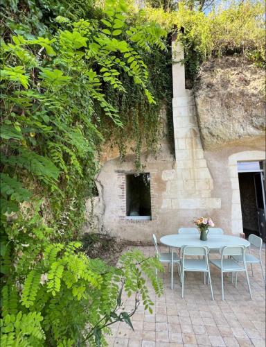 une table et des chaises blanches devant un mur dans l'établissement La petite Troglo, à Aubigné-Racan