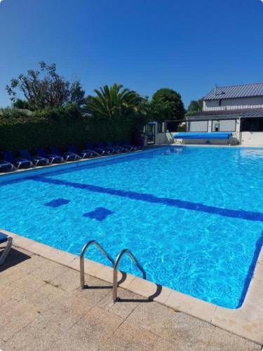 une grande piscine bleue entourée de chaises dans l'établissement Le Bel Air, à Cancale