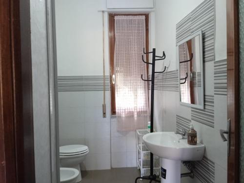 a white bathroom with a toilet and a sink at Appartamento Il Salice in Carignano