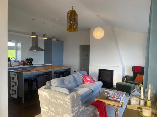 a living room with a couch and a kitchen at West Cork holiday home with incredible sea views in Donoure