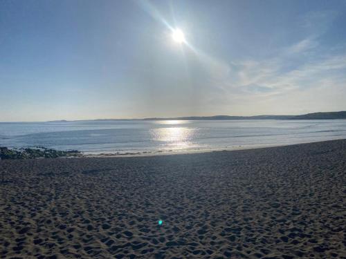 a beach with the sun shining over the water at West Cork holiday home with incredible sea views in Donoure