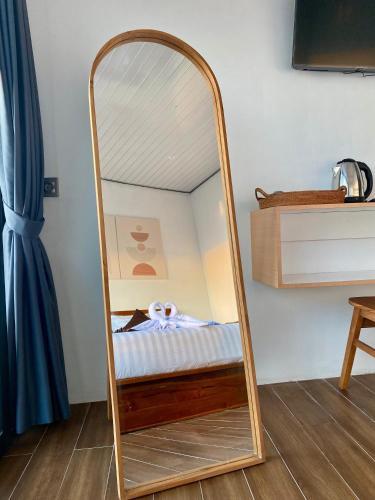 a mirror with a bed in a room at Dbila Cafe, Resto & Hotel in Kintamani