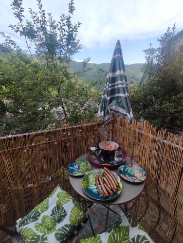 une table avec des assiettes de nourriture et un parapluie dans l'établissement Maison typique de village Corse , 10 min aéroport et de la mer, à Prunelli-di-Casacconi