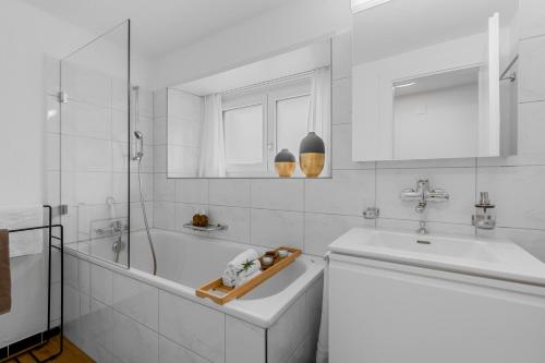 a white bathroom with a tub and a sink at Ferienwohnung 'Rosmarin' Schiers in Schiers