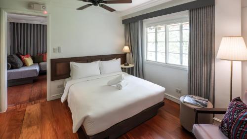 a bedroom with a large white bed and a window at MiraNamin Nest LIRYO Suite in Unique Historic Home - Garden Access, Family Friendly, Shared Kitchen in Manila