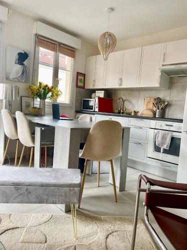 une cuisine avec des armoires blanches et une table et des chaises dans l'établissement Charmant 2p terrasse Paris près sites JO, dont 3 en métro direct Free WIFI, à Paris