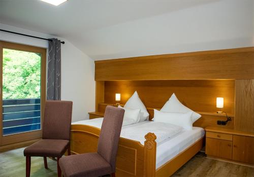 a bedroom with a bed with two chairs and a window at Ferienhaus Wetterstein in Grainau