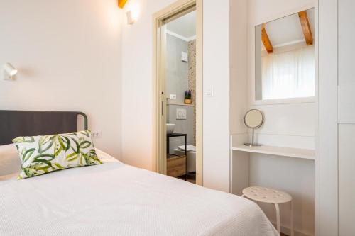 a white bedroom with a bed and a mirror at Skriveni dragulj - A Peaceful Oasis with a Sea View in Trogir