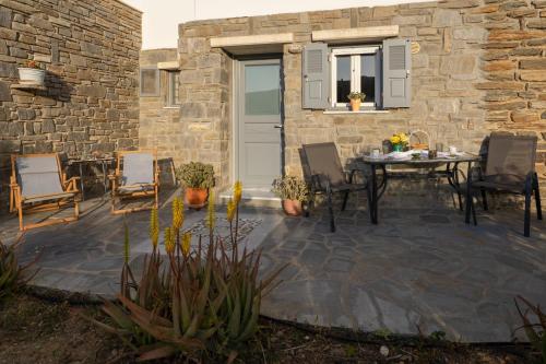 a patio with a table and chairs and a stone wall at Aloni Stone Studio with Private Parking in Lefkes