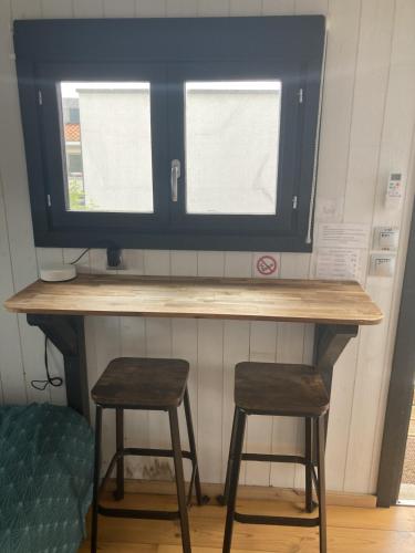 a desk with two stools in front of a window at Le camper Tiny House in Pessac