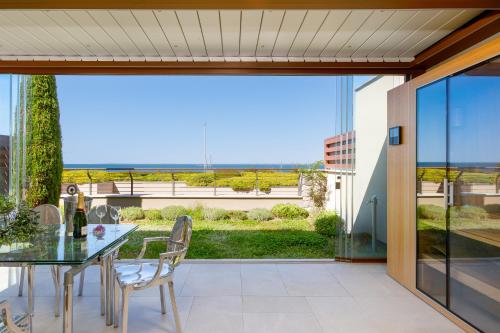 a dining room with a table and chairs and a large window at Portopiccolo Apartments - Giardino vista castello in Portopiccolo Sistiana