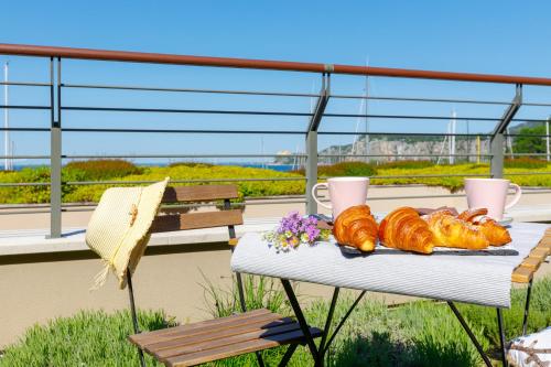 a table with bread and croissants on a balcony at Portopiccolo Apartments - Giardino vista castello in Portopiccolo Sistiana