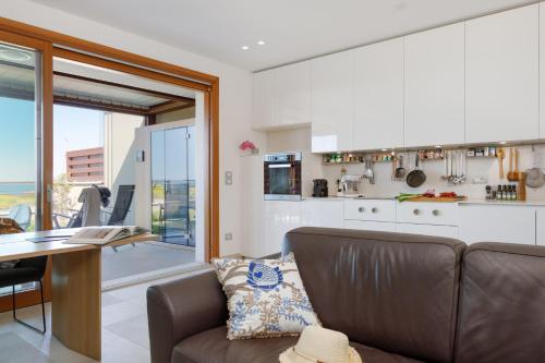 ein Wohnzimmer mit Couch und Küche in der Unterkunft Portopiccolo Apartments - Giardino vista castello in Portopiccolo Sistiana