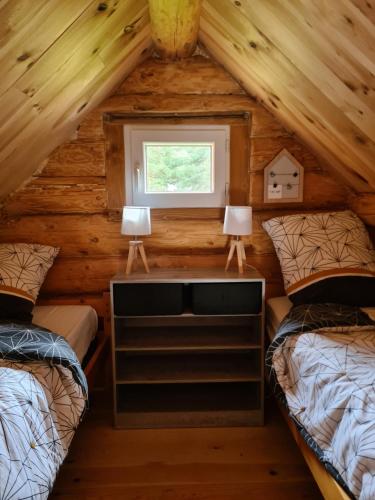 une chambre avec deux lits dans une cabane en rondins dans l'établissement Le chalet du Colibri, à La Celle-sous-Gouzon