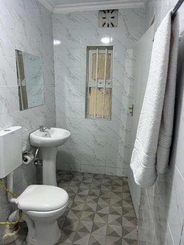 a white bathroom with a toilet and a sink at Dallas auberge in Migori