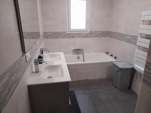 La salle de bains blanche est pourvue d'un lavabo et d'une baignoire. dans l'établissement La Villa les Terrasses du Canal, à Capestang