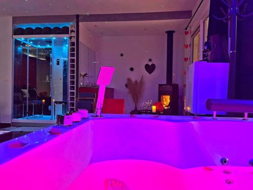 une baignoire rose avec des lumières roses dans une pièce dans l'établissement LoveRoom Var, à Hyères