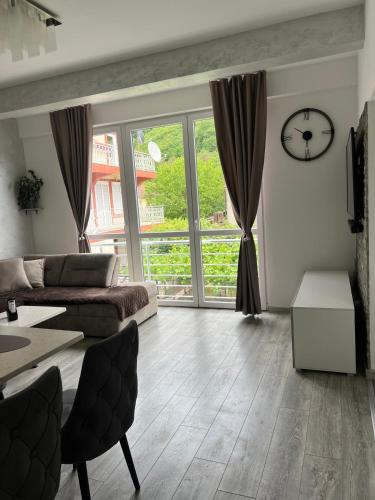 a living room with a couch and a clock on the wall at Apartman Misovic 2 in Zelenika