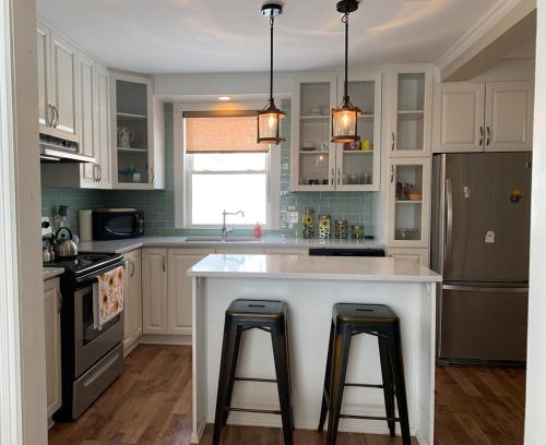 a kitchen with a large white island with two bar stools at Townsite Comfort in Corner Brook