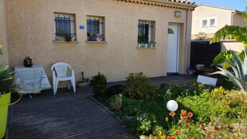 un patio avec une chaise blanche et une table devant une maison dans l'établissement chambre d'amis, à Livron-sur-Drôme