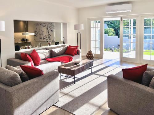una sala de estar con 2 sofás y almohadas rojas en winelands living, en Franschhoek