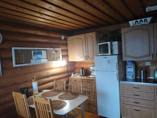 a kitchen with a table and a white refrigerator at Mökki Salakka Rääkkylä Pohjois-Karjala in Nieminen