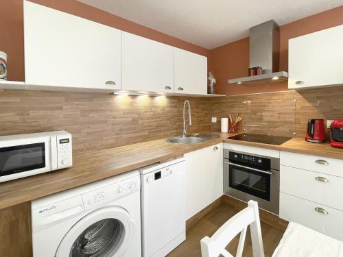une cuisine avec une machine à laver et un évier dans l'établissement Le Vallon des Sources, à Digne-Les-Bains