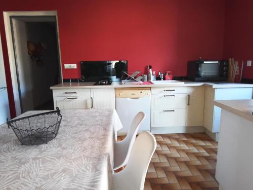 une cuisine avec des murs rouges et une table et des chaises dans l'établissement Location saisonnière dans un cadre calme, à Lalevade-dʼArdèche